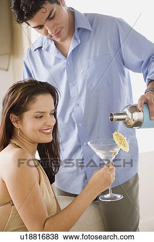 Stock Photo - man pouring cocktail into woman's glass. Fotosearch