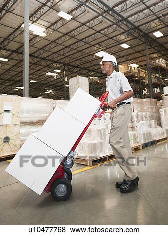 Man pushing hand truck in warehouse View Large Photo Image Stock Photo - Man pushing hand truck in warehouse. Fotosearch