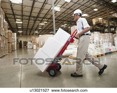 Man pushing hand truck in warehouse View Large Photo Image Stock Photo - Man pushing hand truck in warehouse. Fotosearch