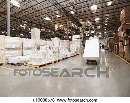 Man pushing hand truck in warehouse View Large Photo Image Stock Photo - Man pushing hand truck in warehouse. Fotosearch