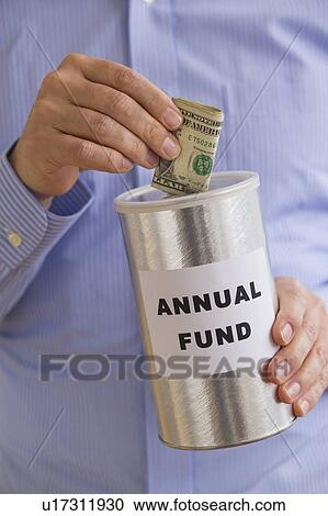 Stock Image - Man putting dollars into annual fund can. Fotosearch