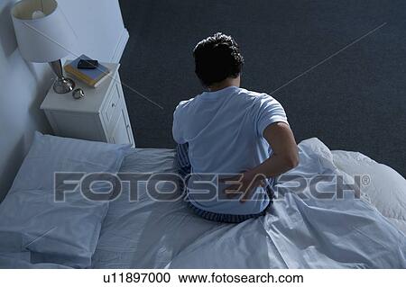 Stock Image - Man sitting on bed . Fotosearch