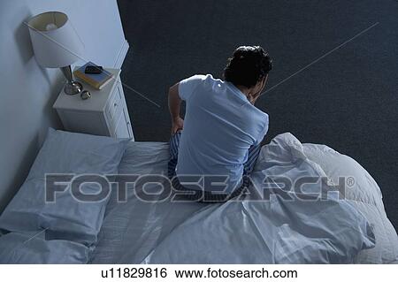 Stock Photograph - Man sitting on bed . Fotosearch