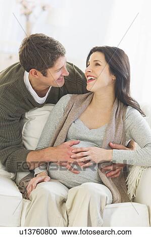 Stock Image - Man touching pregnant woman's belly. Fotosearch