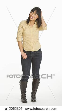 Stock Photography - Mid adult smiling woman standing, studio shot. Fotosearch