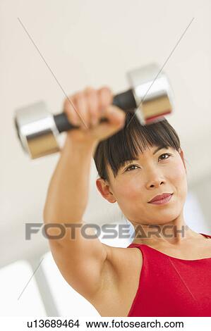 Mid adult woman exercising with dumbbells View Large Photo Image Picture - Mid adult woman exercising with dumbbells. Fotosearch