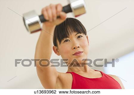 Mid adult woman exercising with dumbbells View Large Photo Image Stock Image - Mid adult woman exercising with dumbbells. Fotosearch