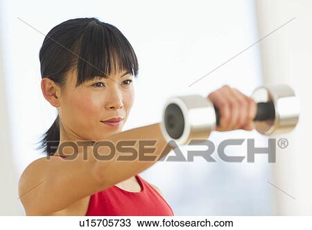 Mid adult woman exercising with dumbbells View Large Photo Image Stock Image - Mid adult woman exercising with dumbbells. Fotosearch