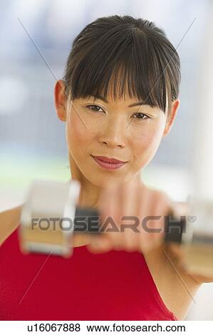 Mid adult woman exercising with dumbbells View Large Photo Image Stock Photo - Mid adult woman exercising with dumbbells. Fotosearch