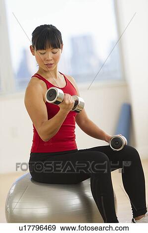 Mid adult woman exercising with dumbbells View Large Photo Image Stock Photo - Mid adult woman exercising with dumbbells. Fotosearch