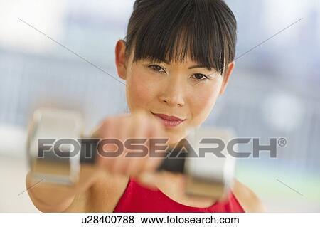 Mid adult woman exercising with dumbbells View Large Photo Image Stock Photo - Mid adult woman exercising with dumbbells. Fotosearch