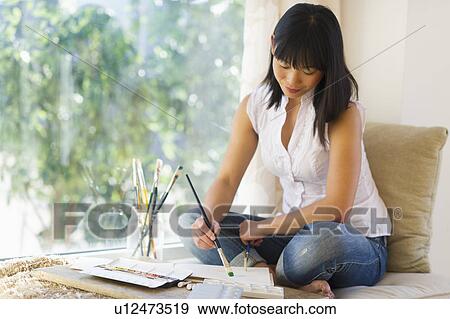 Stock Photo - Mid adult woman painting at home. Fotosearch