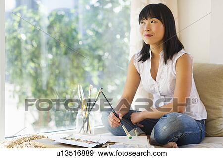 Stock Photo - Mid adult woman painting at home. Fotosearch