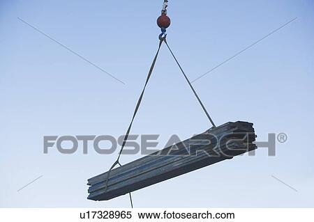 Stock Photography - Mid-air view at crane's hook lifting wooden planks. Fotosearch