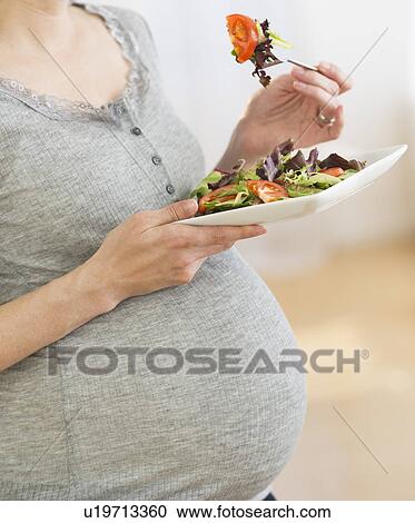 Midsection of pregnant woman eating salad View Large Photo Image Stock Image - Midsection of pregnant woman eating salad. Fotosearch