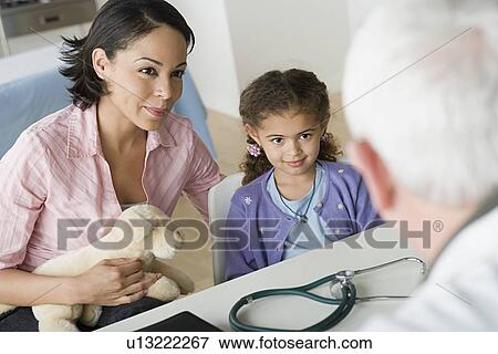 Stock Photo - Mother and daughter (10-11) talking to doctor. Fotosearch