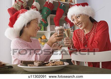 Mother and daughter wearing santa hats toasting with drinks View Large Photo Image Stock Image - Mother and daughter wearing santa hats toasting with drinks. Fotosearch