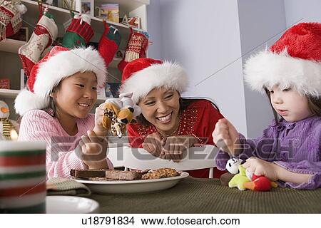 Picture - Mother with two daughters playing at Christmas morning. Fotosearch