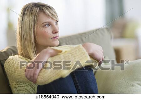 Stock Image - Pensive woman sitting on sofa. Fotosearch