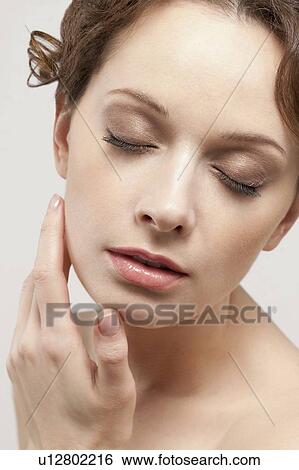 Stock Photograph - Portrait of beautiful young woman with eyes closed, studio shot. Fotosearch