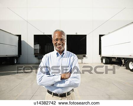 Stock Image - Portrait of businessman outside warehouse. Fotosearch