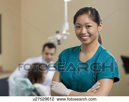 Stock Image - Portrait of dentist, dentist and patient in background. Fotosearch