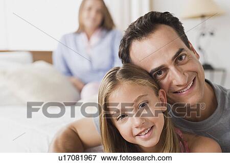 Portrait of father and daughter with mother in background View Large Photo Image Stock Photo - Portrait of father and daughter with mother in background. Fotosearch