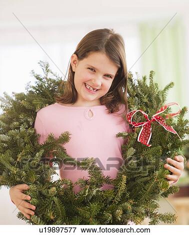 Stock Photo - Portrait of girl (8-9) with christmas wreath. Fotosearch