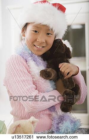Stock Image - Portrait of girl wearing santa hat. Fotosearch