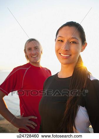 Stock Image - Portrait of male and female joggers at sea. Fotosearch