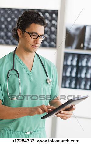 Stock Image - Portrait of male doctor using digital tablet. Fotosearch