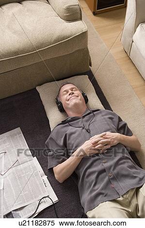 Stock Photography - Portrait of man lying on floor with headphones. Fotosearch