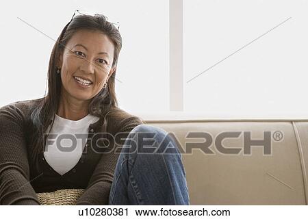 Portrait of mature woman sitting on sofa View Large Photo Image Stock Image - Portrait of mature woman sitting on sofa. Fotosearch