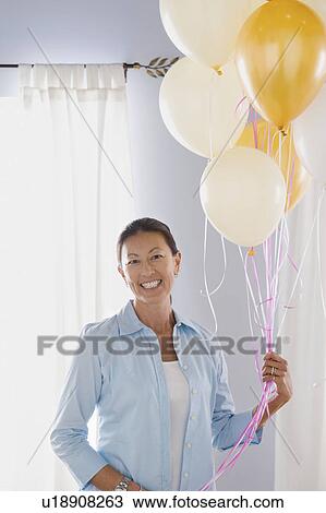 Stock Image - Portrait of mature woman with balloons. Fotosearch