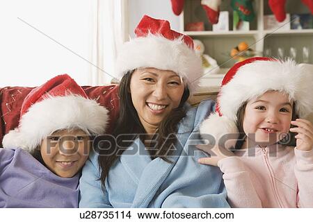 Portrait of mother with two daughters (10-11) wearing Santa hats View Large Photo Image Picture - Portrait of mother with two daughters (10-11) wearing Santa hats. Fotosearch