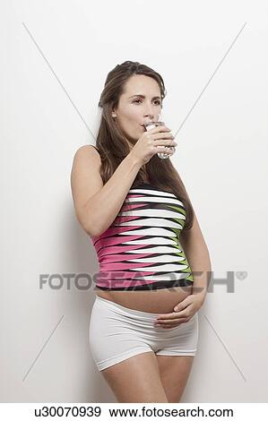 Stock Photo - Portrait of pregnant woman drinking water, studio shot. Fotosearch