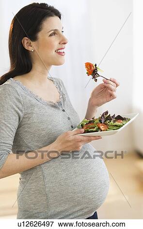 Stock Photo - Portrait of pregnant woman eating salad. Fotosearch