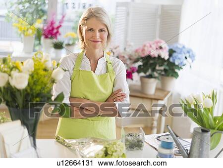Stock Image - Portrait of senior female florist in flower shop. Fotosearch