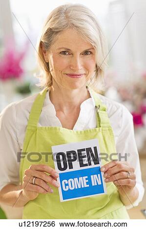 Portrait of senior female florist showing open sign and smiling View Large Photo Image Stock Photograph - Portrait of senior female florist showing open sign and smiling. Fotosearch