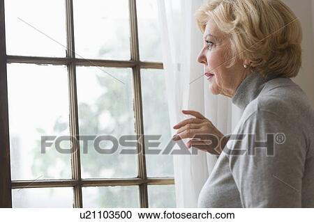 Portrait of senior woman looking through window View Large Photo Image Stock Image - Portrait of senior woman looking through window. Fotosearch