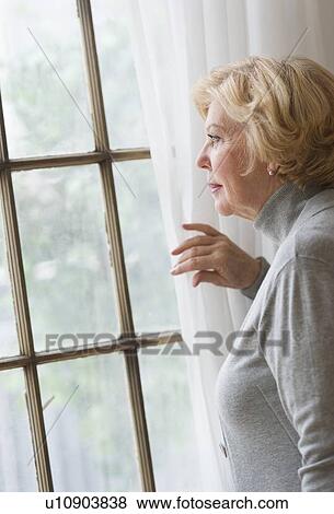 Portrait of senior woman looking through window View Large Photo Image Stock Photo - Portrait of senior woman looking through window. Fotosearch