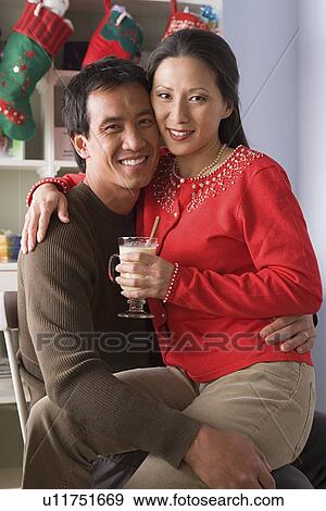 Stock Photo - Portrait of smiling couple, Christmas stockings in background. Fotosearch