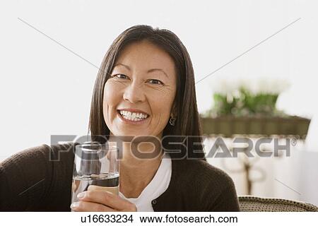 Portrait of smiling woman holding glass of water View Large Photo Image Picture - Portrait of smiling woman holding glass of water. Fotosearch