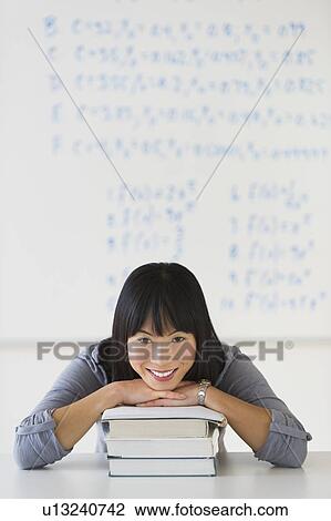 Stock Image - Portrait of smiling woman in front of board with equations. Fotosearch