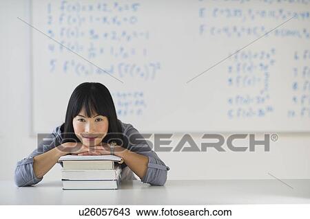 Stock Image - Portrait of smiling woman in front of board with equations. Fotosearch