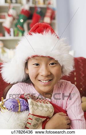 Stock Photograph - Portrait of teenage Girl (10-11) wearing santa hat. Fotosearch