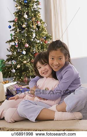 Portrait of two sisters (10-11) hugging at Christmas tree View Large Photo Image Stock Photo - Portrait of two sisters (10-11) hugging at Christmas tree. Fotosearch