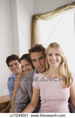 Portrait of two smiling couples sitting on sofa View Large Photo Image Stock Image - Portrait of two smiling couples sitting on sofa. Fotosearch