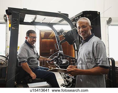Portrait of warehouse workers by forklift truck View Large Photo Image Stock Image - Portrait of warehouse workers by forklift truck. Fotosearch