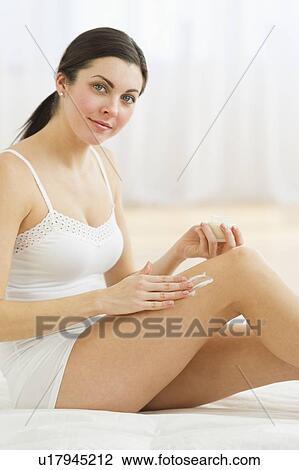 Stock Image - Portrait of woman applying moisturizer. Fotosearch
